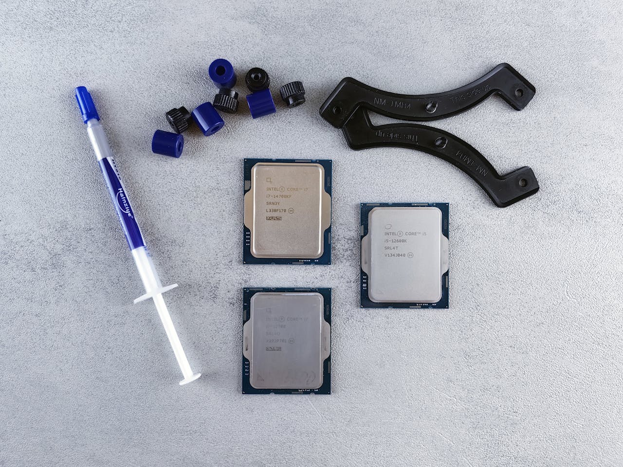 Top view of computer CPUs and thermal paste on a gray surface, showcasing modern technology components.